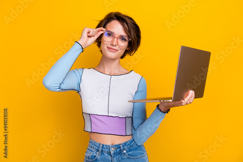 Portrait of lovely intelligent girl touch eyeglasses hold laptop coworking isolated on yellow color background