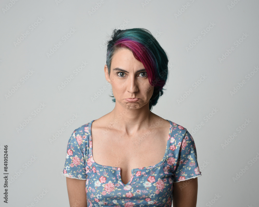 a close up head and shoulders portrait of young alternative female model, with pink and grey shaved undercut hair style, wearing a floral blue top. dramatically pulling expressive facial expressions. a close up head and shoulders portrait of young alternative female model, with pink and grey shaved undercut hair style, wearing a floral blue top. dramatically pulling expressive facial expressions.