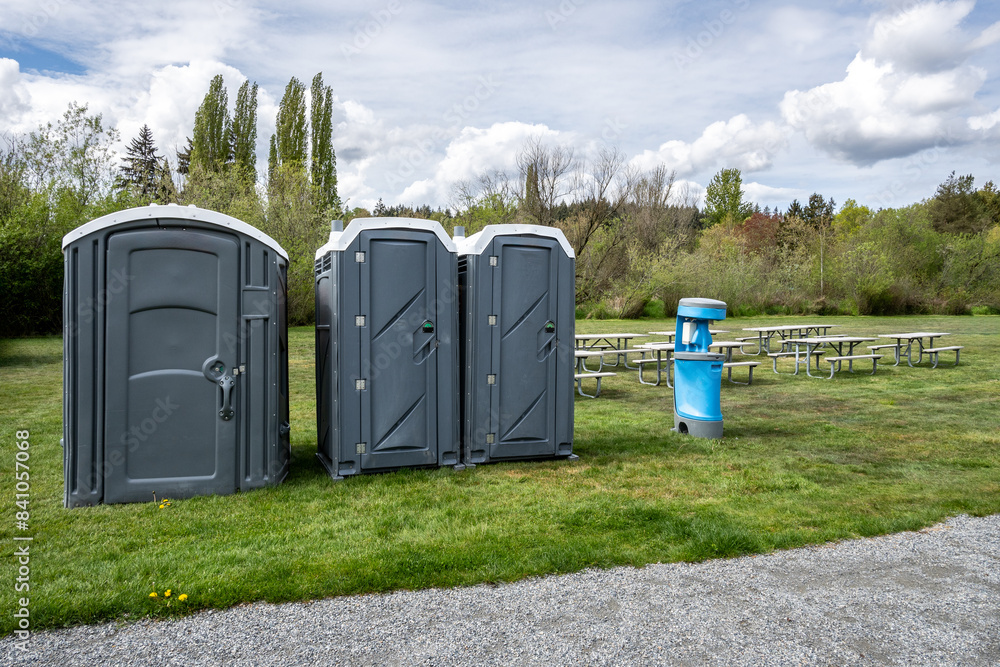 Setting up for a spring festival in a grass field in the park, picnic tables, portable bathrooms, and handwashing and sanitation station, sunny day outside
Setting up for a spring festival in a grass field in the park, picnic tables, portable bathrooms, and handwashing and sanitation station, sunny day outside