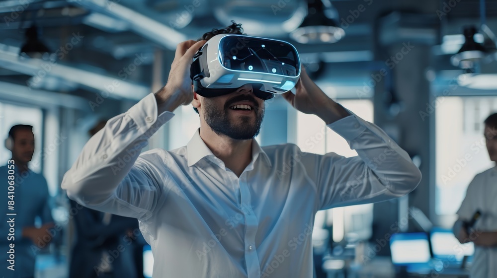 A young, triumphant male engineer, removing his futuristic VR headset, proudly showcases a successfully completed virtual project to his colleagues. A young, triumphant male engineer, removing his futuristic VR headset, proudly showcases a successfully completed virtual project to his colleagues.