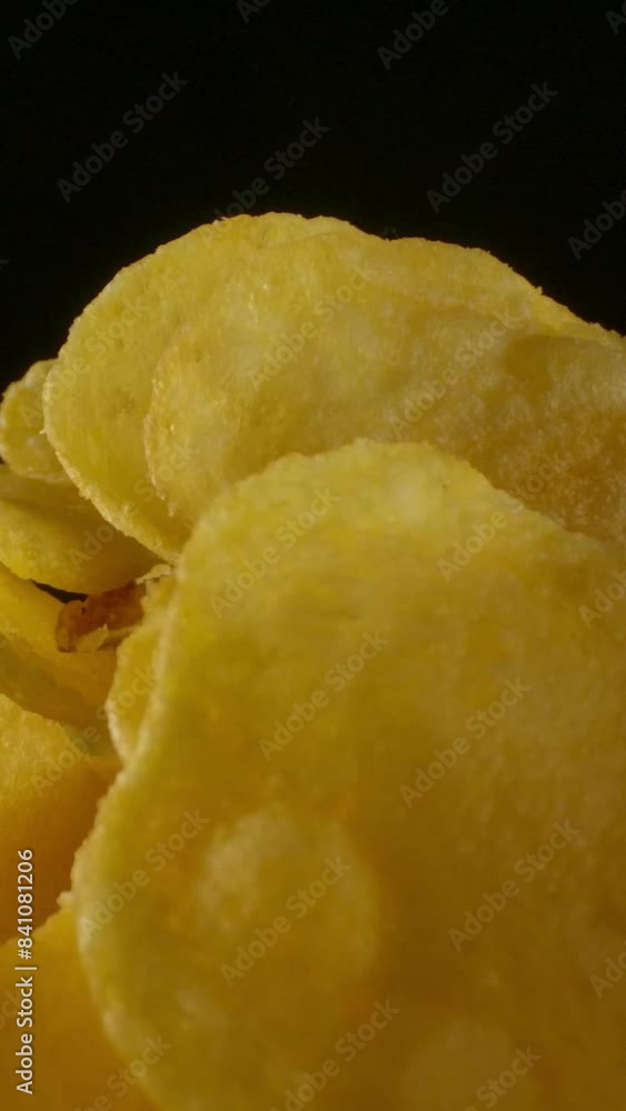 Closeup portion of crispy and salty potato chips placed in bowl in dark room. Vertical shot. Closeup portion of crispy and salty potato chips placed in bowl in dark room. Vertical shot.