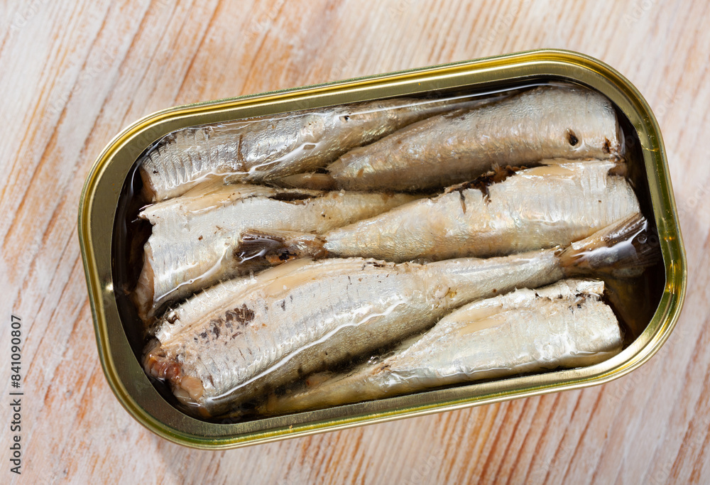 Φωτογραφία Canned sea fish, sardines in marinade of oil in opened can on wooden table