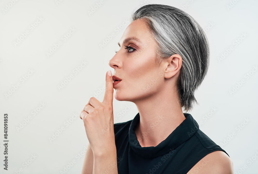 Fashion, studio and mature woman with secret hand sign for privacy, silence and gossip on white background. Female person, whisper and quiet gesture for rumor, mystery and confidentiality or hush Fashion, studio and mature woman with secret hand sign for privacy, silence and gossip on white background. Female person, whisper and quiet gesture for rumor, mystery and confidentiality or hush