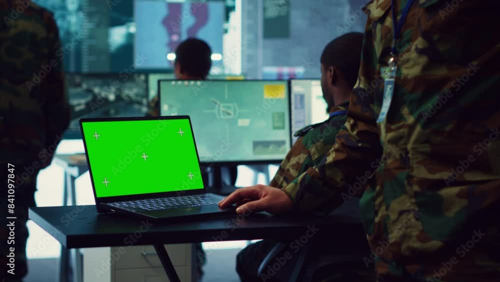Army officer studies isolated greenscreen display on a laptop in control room, military power base personnel monitoring satellite world map for federal operations. Commander in uniform. Camera A. Army officer studies isolated greenscreen display on a laptop in control room, military power base personnel monitoring satellite world map for federal operations. Commander in uniform. Camera A.