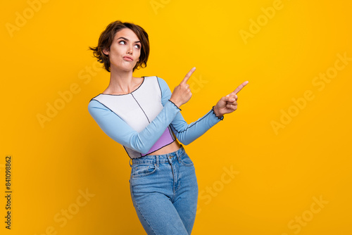 Photo of doubtful pretty woman wear top showing two fingers looking empty space isolated yellow color background
