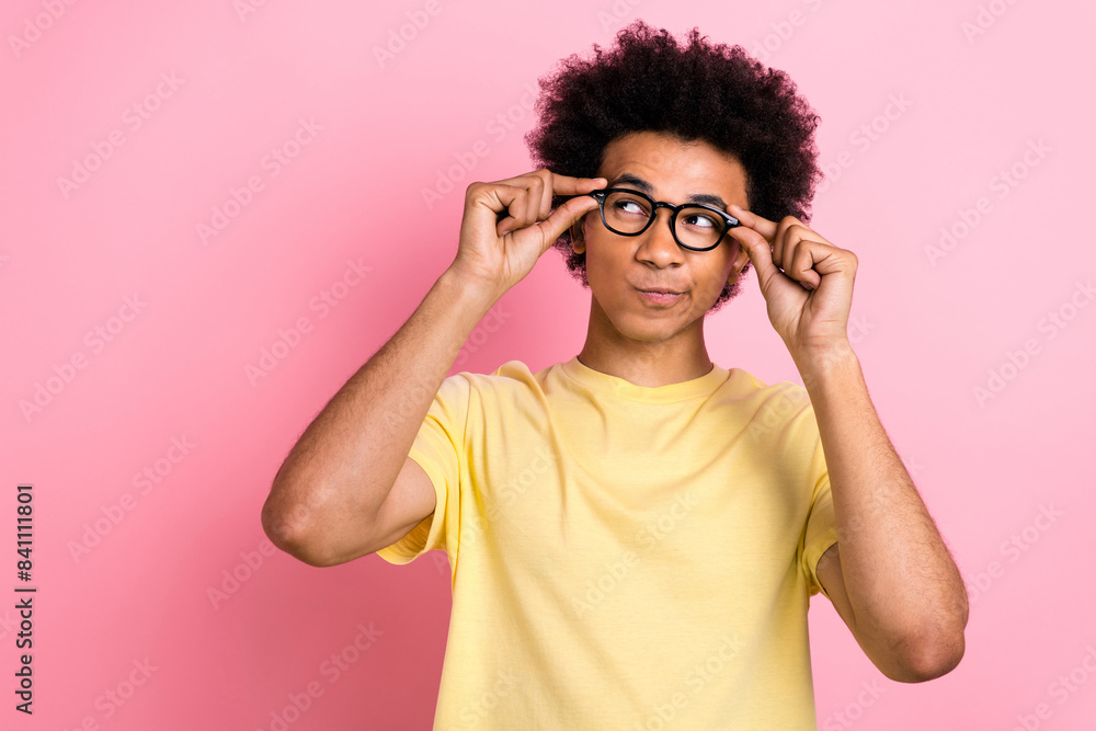 Photo of adorable doubtful guy dressed yellow t-shirt arms eyewear looking empty space isolated pink color background Photo of adorable doubtful guy dressed yellow t-shirt arms eyewear looking empty space isolated pink color background