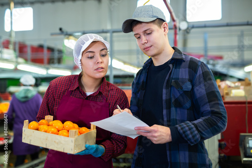 Workers fill out documents and discusses the process of sorting  packaging and quality control of fruit.