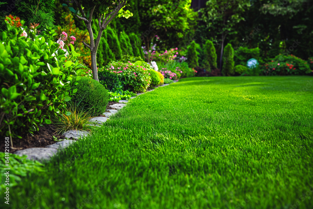 Beautiful manicured lawn and flowerbed with deciduous shrubs on plot or Park outdoor. Green lawn closely mowed as grass background. Beautiful manicured lawn and flowerbed with deciduous shrubs on plot or Park outdoor. Green lawn closely mowed as grass background.