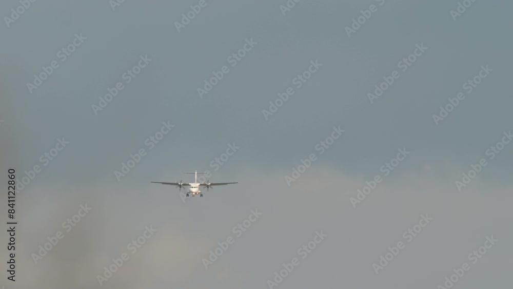 Airplane approaching. Turboprop passenger aircraft flying, front view. Landing airplane. Blue sky background Airplane approaching. Turboprop passenger aircraft flying, front view. Landing airplane. Blue sky background