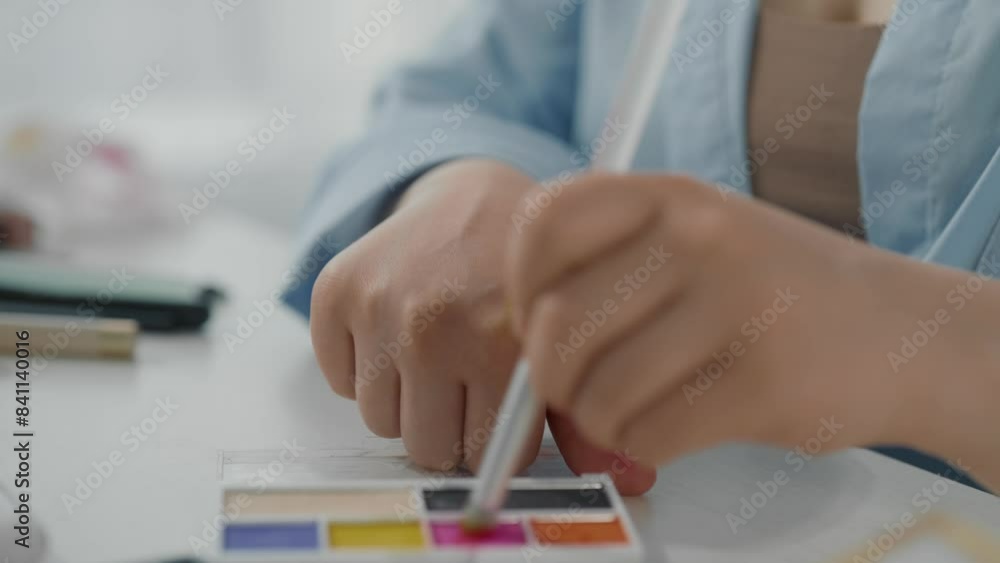 Closeup view of young lady hands and bright eyeshadow palette in beauty studio. Professional makeup artist taking bright color by cosmetic brush and applying on skin of hand, swatch of eyeshadows Closeup view of young lady hands and bright eyeshadow palette in beauty studio. Professional makeup artist taking bright color by cosmetic brush and applying on skin of hand, swatch of eyeshadows