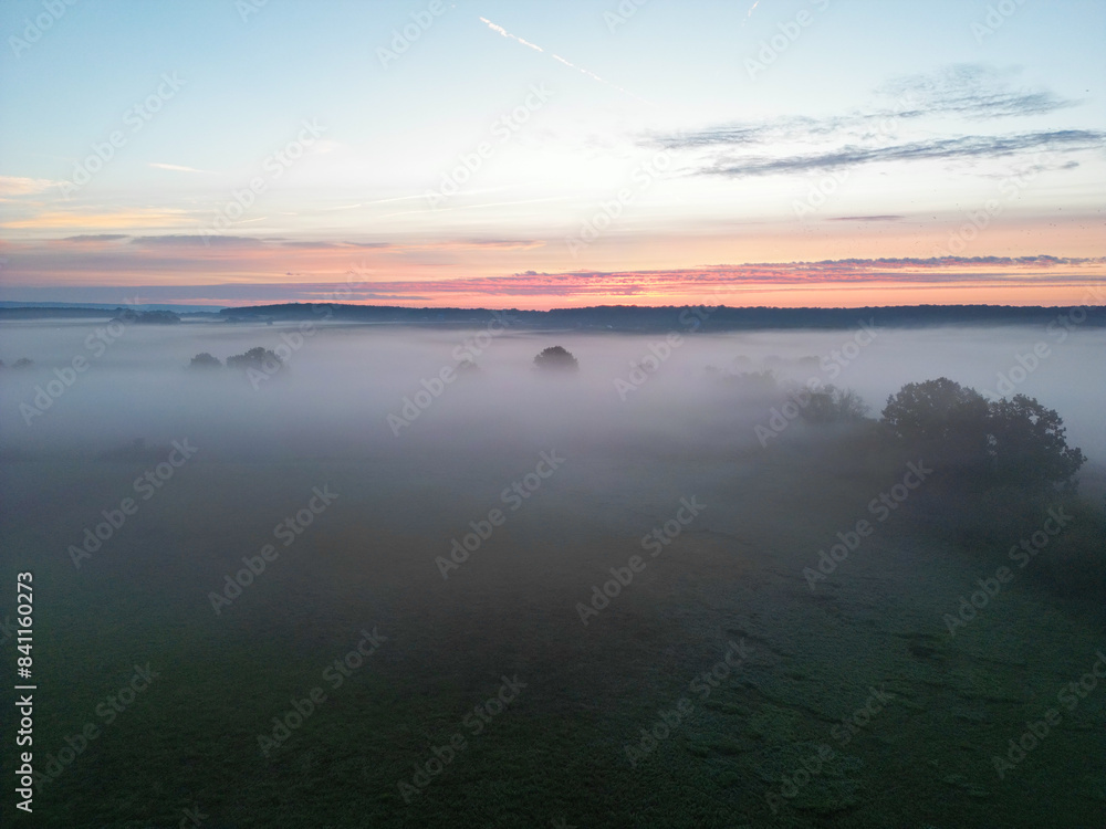 Obraz premium Sonnenaufgang über Schweinfurt mit Nebelschleiern, Nebel über den Feldern, mit einem Bach und Bäumen und die aufgehende Sonne am Horizont, Drohnenfoto, Luftaufnahme, Schweinfurt, Bayern, Deutschland