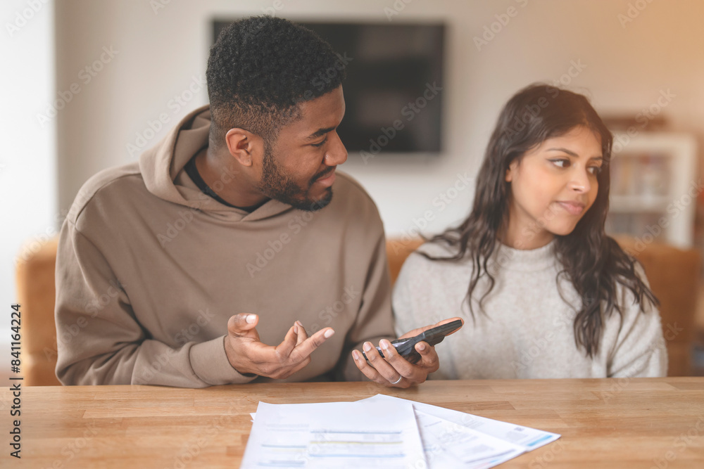 A couple sits at a table, discussing finances with a serious expression. Moment of financial discussion in a cozy home A couple sits at a table, discussing finances with a serious expression. Moment of financial discussion in a cozy home