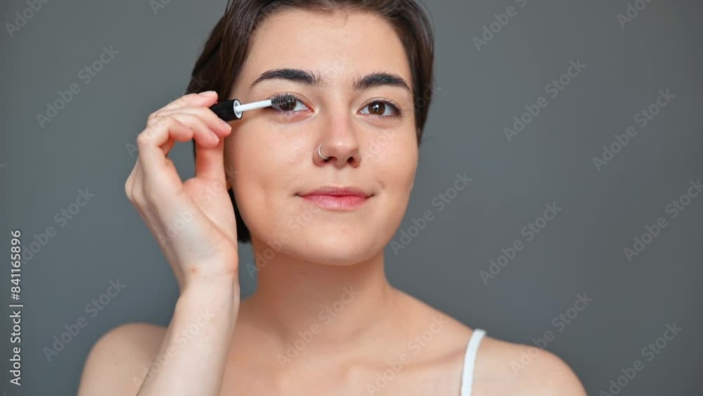 Beautiful young woman doing make-up, painting black eyelashes. Female beauty Beautiful young woman doing make-up, painting black eyelashes. Female beauty
