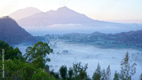 Fog on mountains scenery at sunrise with soft and warm morning light. Natural nature landscape background. Kintamani, Bali.