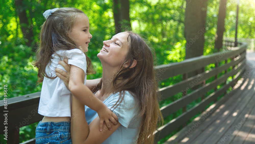 Naklejka premium Mother and daughter have fun in the park. Happy family concept. Beauty nature scene with family outdoor lifestyle.