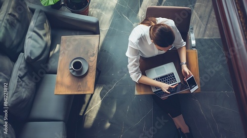 Top view young business woman in white shirt sitting at desk and working online on laptop while using smartphone On table cup of coffeeStudent learning online Girl shopping online chec : Generative AI photo