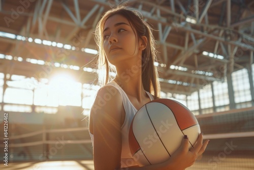 A woman holds a volleyball ball in a stadium, possibly during a game or practice photo