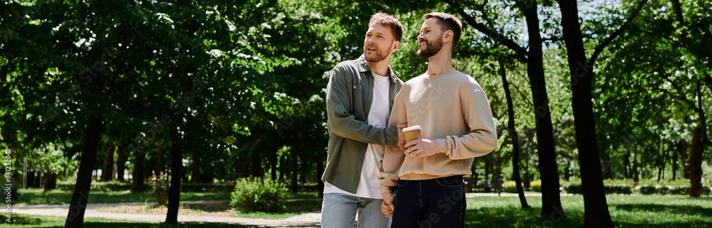 Two bearded gay men in casual attire are walking together in a green park on a sunny day.