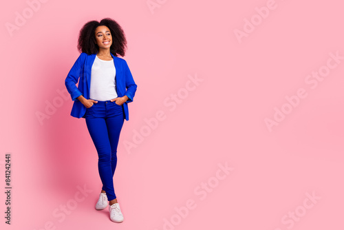 Full length photo of pretty woman with perming coiffure wear suit blue jacket look at promo empty space isolated on pink color background