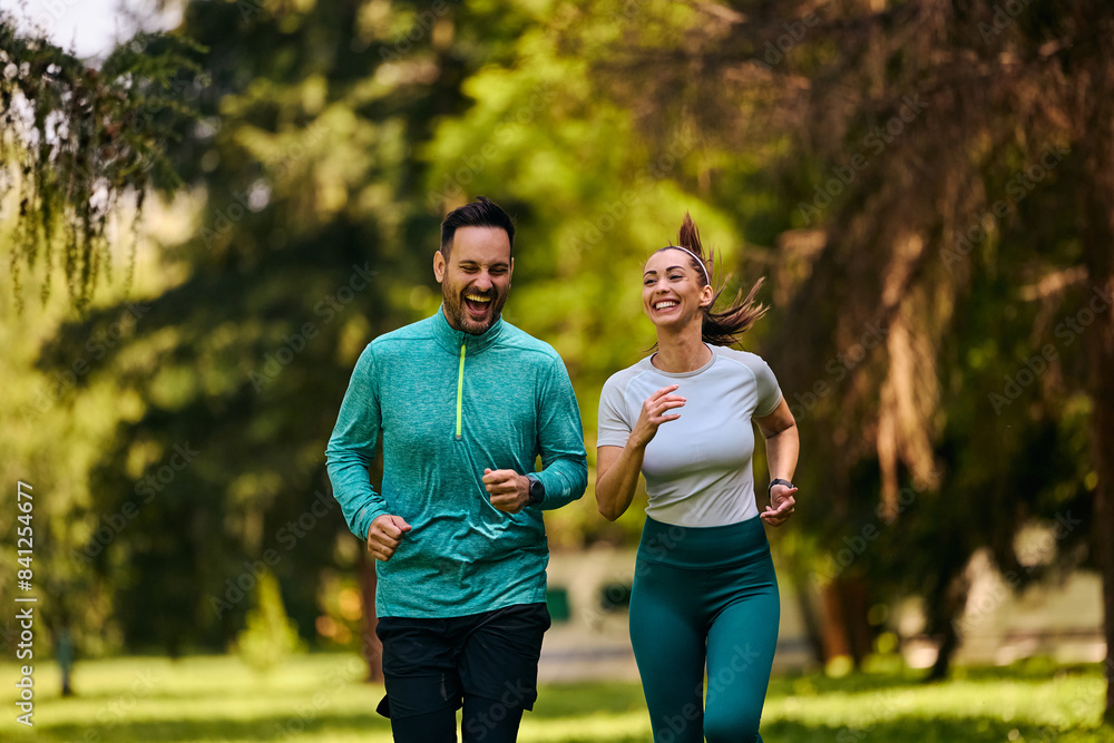 Athletic couple laughing and having fun while jogging in nature. Athletic couple laughing and having fun while jogging in nature.