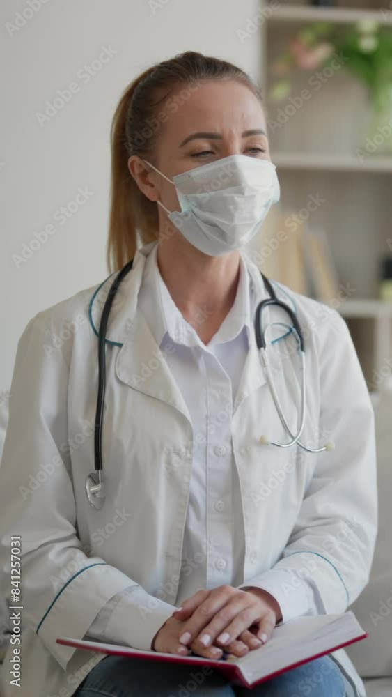 Female health professional with surgical face mask in home of patient, vertical video, portrait. Offline consultation with therapist, emergency doctor, epidemic of respiratory viruses, healthcare Female health professional with surgical face mask in home of patient, vertical video, portrait. Offline consultation with therapist, emergency doctor, epidemic of respiratory viruses, healthcare