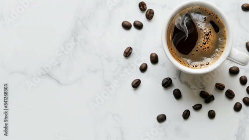 top down view of a steaming cup of black coffee on a white marble surface, surrounded by coffee beans