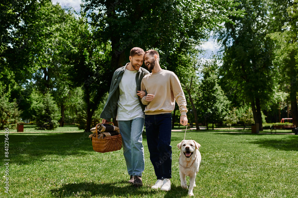 A bearded gay couple walks through a green park with their labrador retriever. They are both smiling and appear to be enjoying each others company. A bearded gay couple walks through a green park with their labrador retriever. They are both smiling and appear to be enjoying each others company.