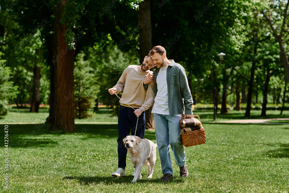 A bearded gay couple walks through a green park with their labrador dog, enjoying a sunny day. A bearded gay couple walks through a green park with their labrador dog, enjoying a sunny day.