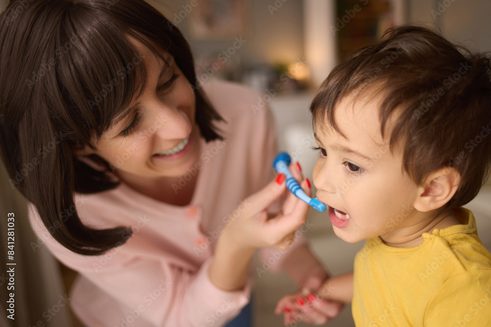 Mother teaching and helping her son brush his teeth at home Mother teaching and helping her son brush his teeth at home