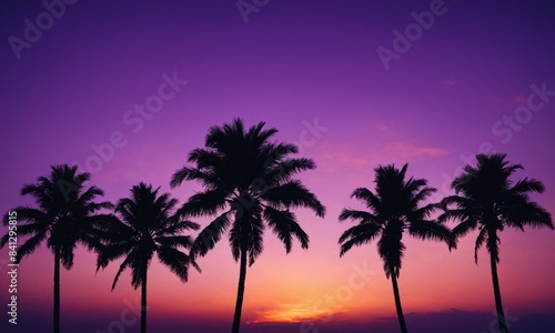 Silhouettes of palm trees against a purple sunset