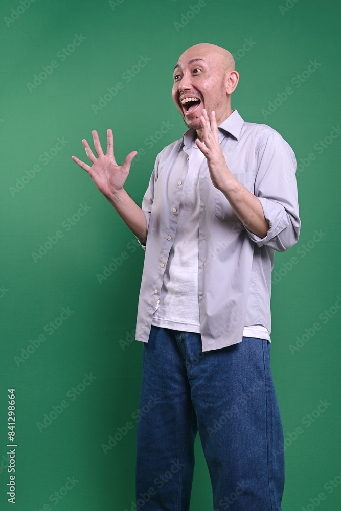 Adult Asian Bald Man Standing Against Green Background With Surprise Expression