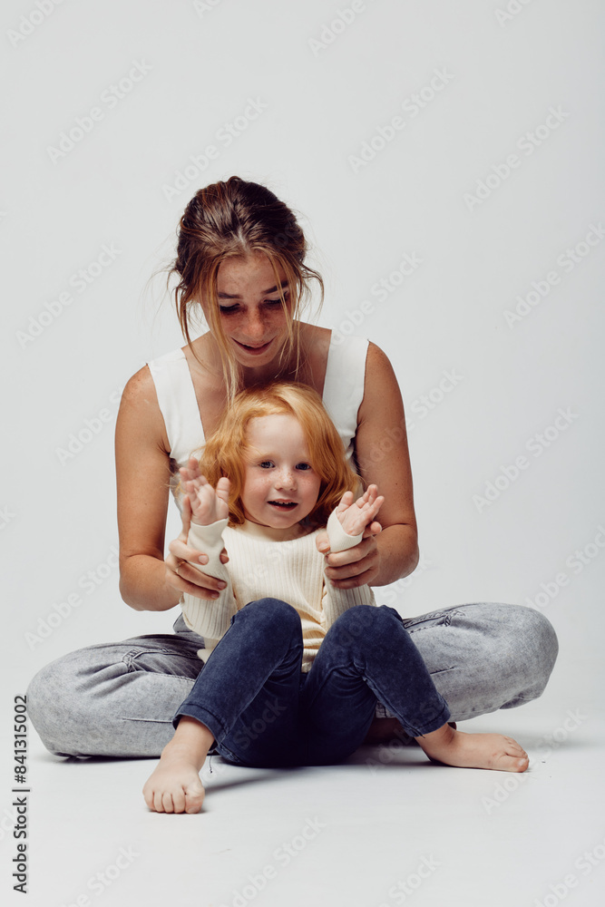 Family fun time mother and daughter playing a silly game on the floor together with raised hands Family fun time mother and daughter playing a silly game on the floor together with raised hands