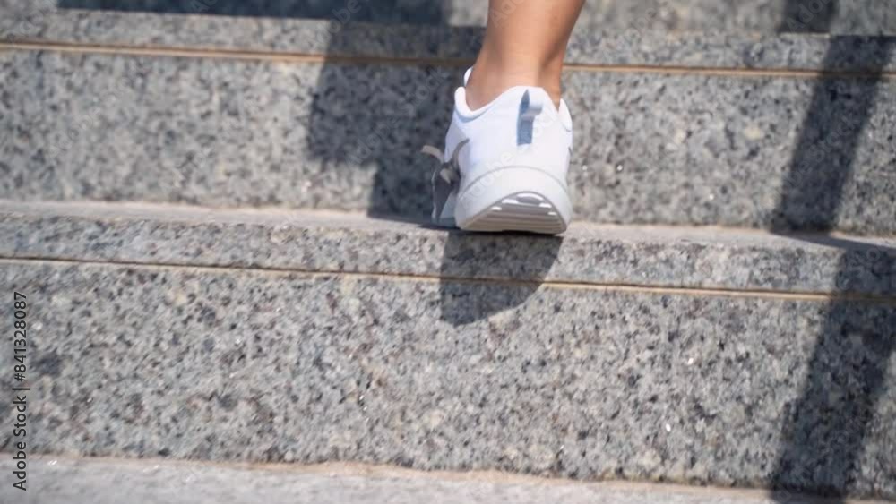 Close-up female teenager girl legs with sport shoes sneakers climd step the stairs. Rear view. Woman hurry up walking staircase sunny warm weather outdoors Close-up female teenager girl legs with sport shoes sneakers climd step the stairs. Rear view. Woman hurry up walking staircase sunny warm weather outdoors