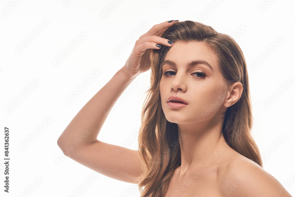 A stunning young woman with long, wavy hair strikes a captivating pose for the camera. A stunning young woman with long, wavy hair strikes a captivating pose for the camera.