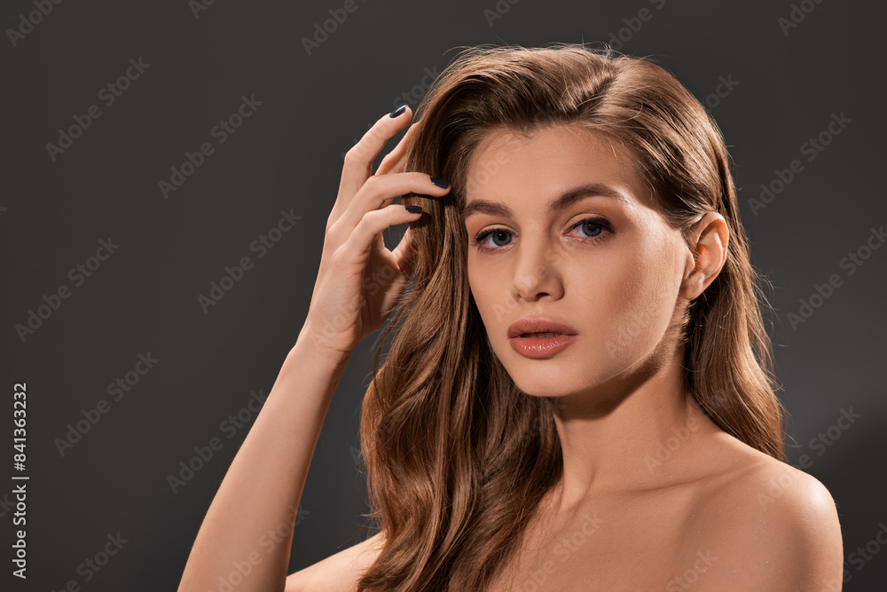 Naklejka premium A young, beautiful woman with long, wavy brown hair strikes a pose for a portrait.