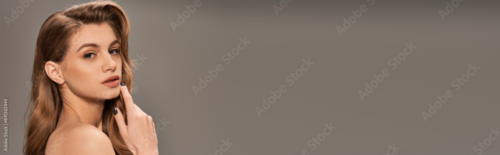 Obraz premium A young woman with long, wavy hair poses gracefully for a portrait, exuding elegance and beauty, banner.