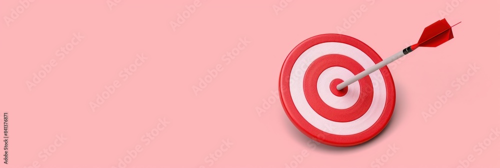 A red arrow has hit the center of a white and red bullseye target against a pink background A red arrow has hit the center of a white and red bullseye target against a pink background