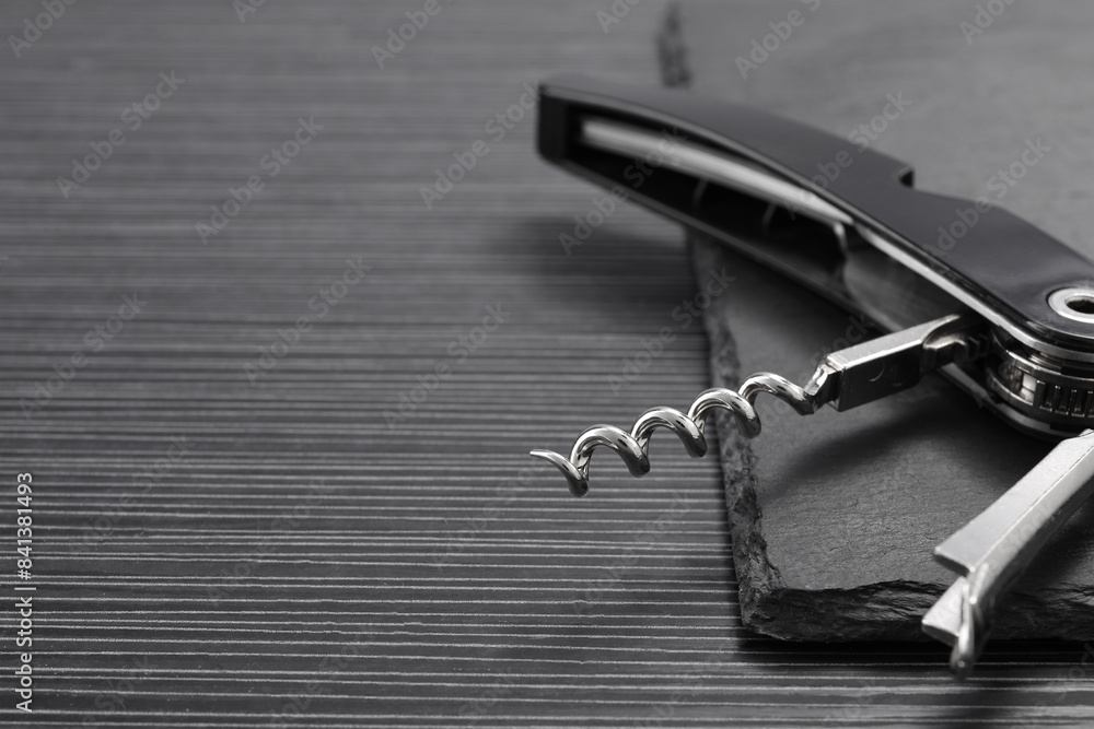 One corkscrew (sommelier knife) on black wooden table, closeup. Space for text One corkscrew (sommelier knife) on black wooden table, closeup. Space for text