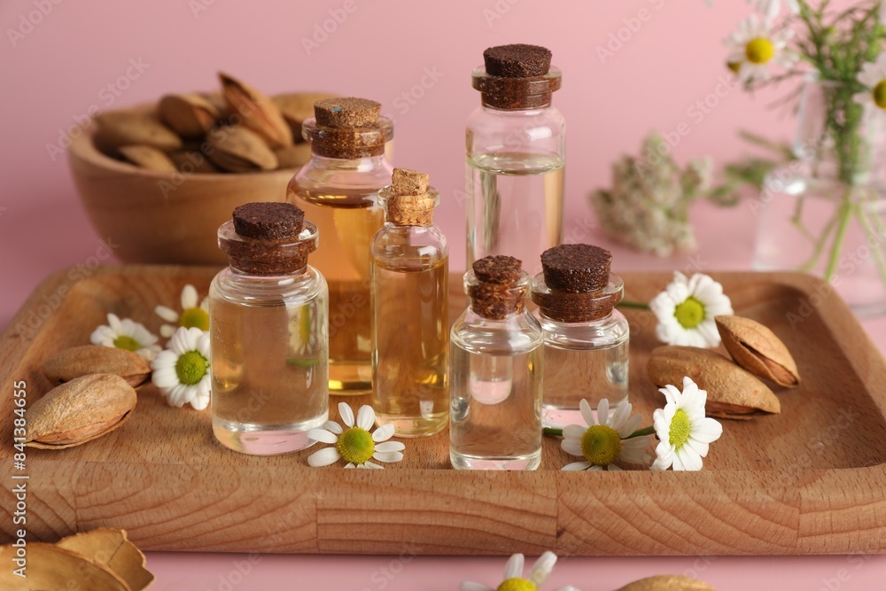 Aromatherapy. Different essential oils, flowers and almonds on pink background Aromatherapy. Different essential oils, flowers and almonds on pink background