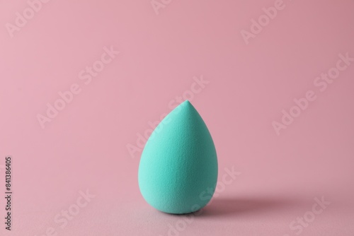 One turquoise makeup sponge on pink background