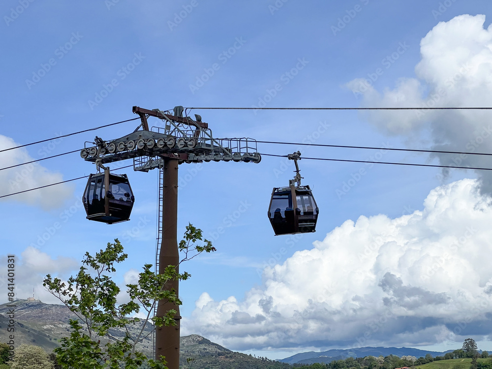 Two cable cars are suspended from a tall pole Two cable cars are suspended from a tall pole