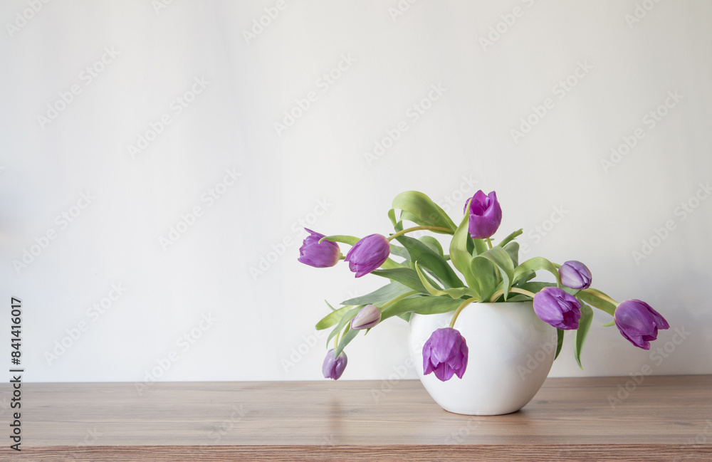 purple tulips in white ceramic vase on wooden shelf purple tulips in white ceramic vase on wooden shelf