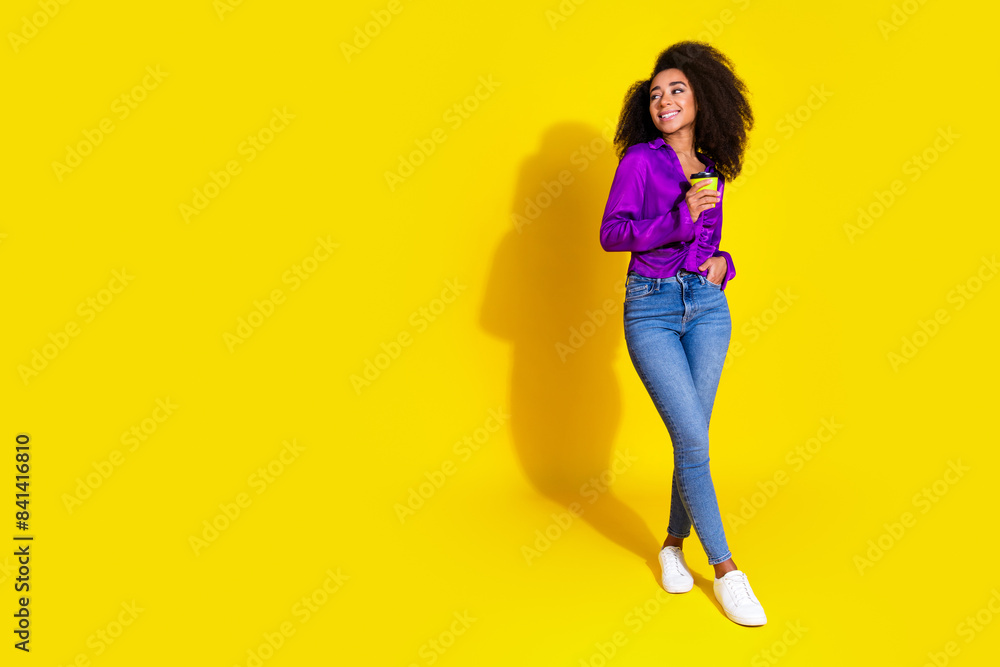Full body photo of lovely lady hold coffee paper cup look empty space dressed stylish violet garment isolated on yellow color background Full body photo of lovely lady hold coffee paper cup look empty space dressed stylish violet garment isolated on yellow color background