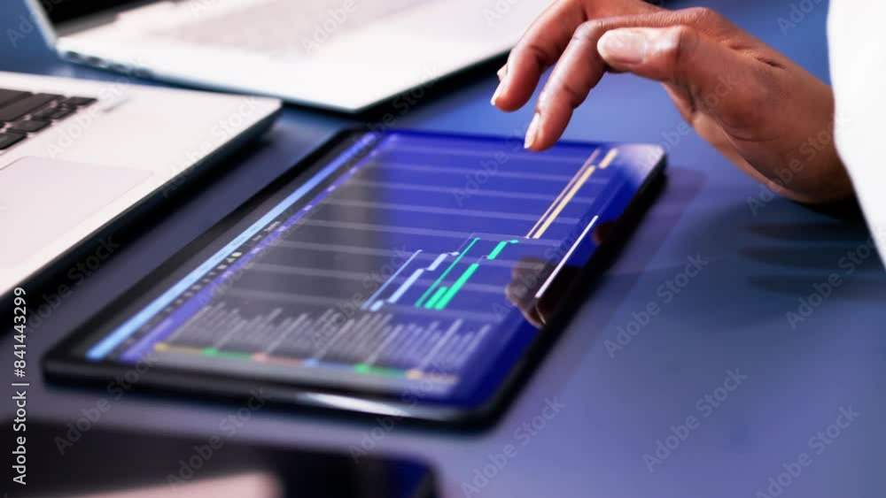 African American woman using Gantt software to manage project schedule and control finances on computer