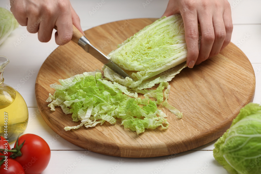 Woman cutting fresh chinese cabbage at white wooden table, closeup Woman cutting fresh chinese cabbage at white wooden table, closeup