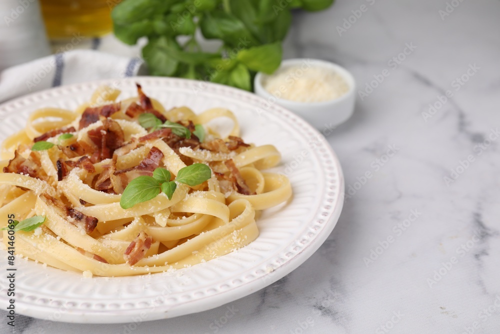 Tasty pasta with bacon and basil on white marble table, space for text Tasty pasta with bacon and basil on white marble table, space for text