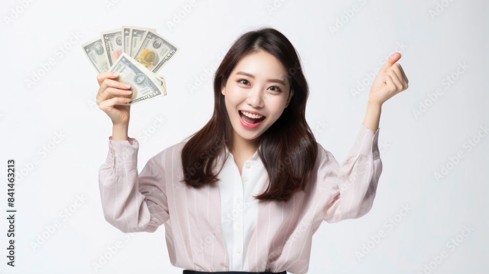 Excited young woman holding cash with a cheerful expression, celebrating financial success and wealth. Isolated on white background. Excited young woman holding cash with a cheerful expression, celebrating financial success and wealth. Isolated on white background.