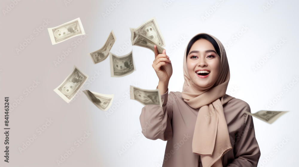 Excited young woman in hijab throwing dollar bills in the air, celebrating financial success and wealth. Excited young woman in hijab throwing dollar bills in the air, celebrating financial success and wealth.