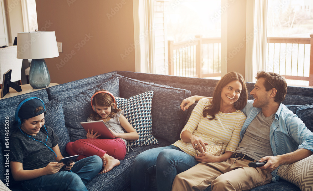 Family, children and parents with popcorn, sofa and streaming on tablet with bonding in living room. Woman, man and kids with headphones, happy and watching tv to relax with film on couch at house