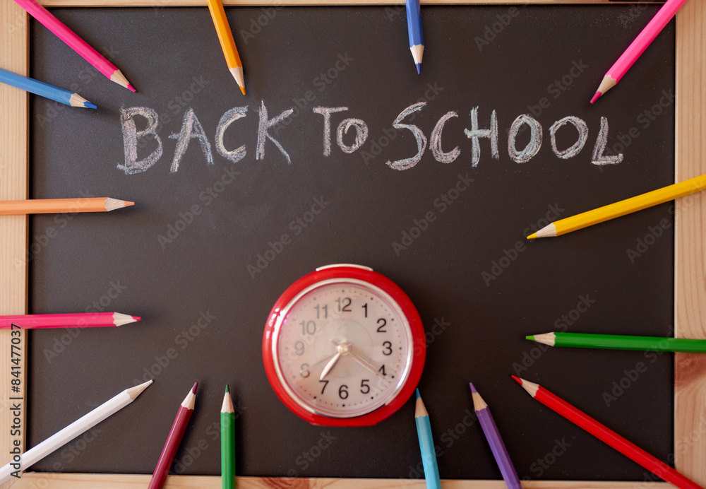 back to School message on blackboard with a clock and colourful pencils around back to School message on blackboard with a clock and colourful pencils around